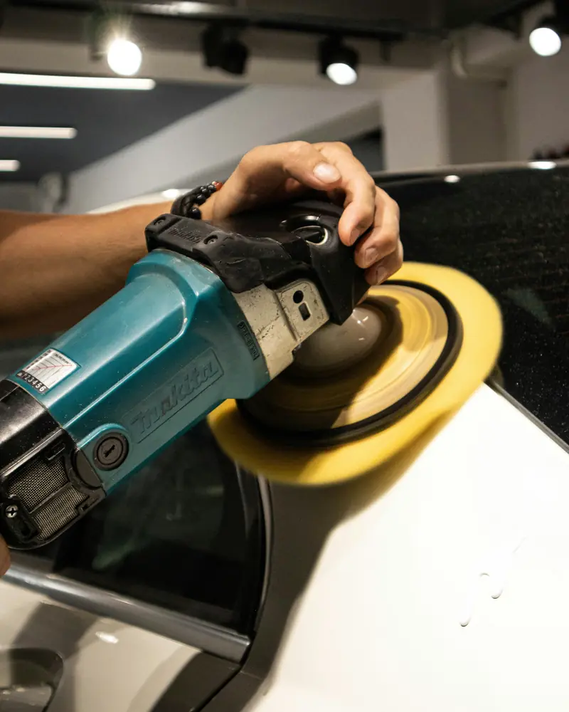 A rotary polisher with a yellow pad on white paintwork